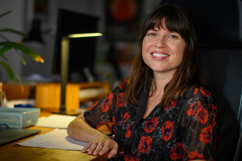 Ana Penyas sentada con el brazo apoyado en una mesa alumbrada por una lámpara de escritorio